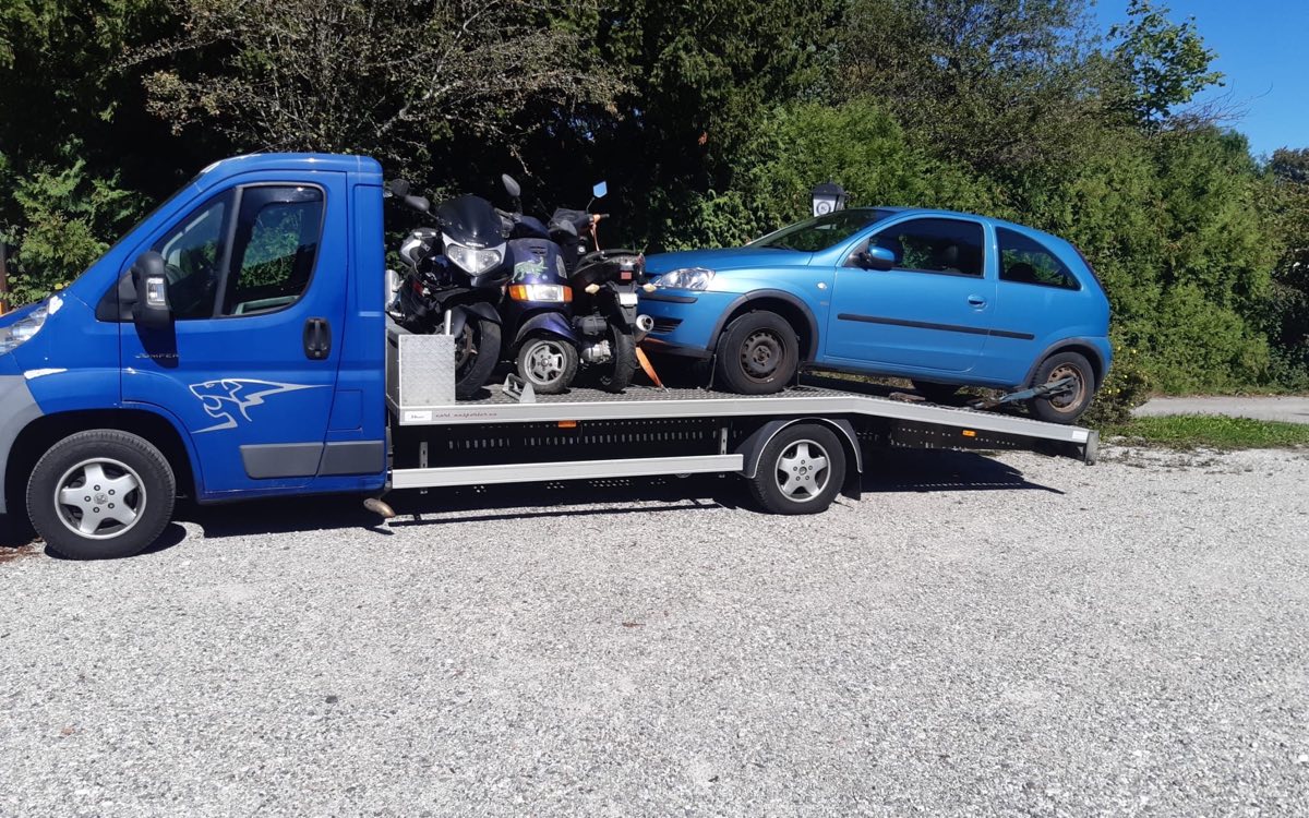 Auto und Motorräder auf dem Abholtransporter